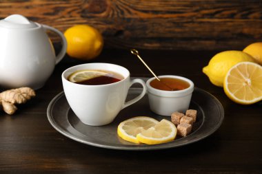 Bir fincan siyah çay, limon, kamış şekeri ve bal ile koyu ahşap zemin üzerinde