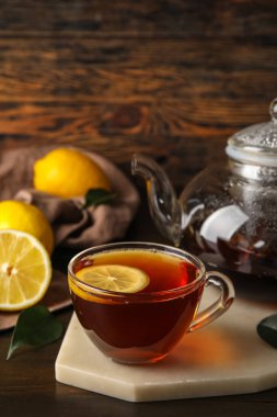 Koyu ahşap arka planda cam çay ve limon dolu tahta pano, yakın plan.