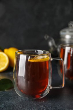 Koyu arkaplanda limonlu bir bardak siyah çay, yakın plan.