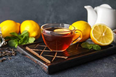 Koyu arkaplanda cam bardak çay, limon ve nane, yakın plan.