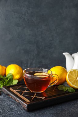 Koyu arkaplanda cam çay, limon ve nane olan tahta.