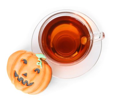 Cadılar Bayramı balkabağı kurabiyesi ve beyaz arka planda bir fincan çay.