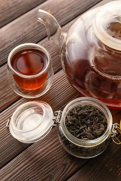 Bardak ve çaydanlık siyah çay ve ahşap arka planda kurumuş yapraklar, yakın plan.