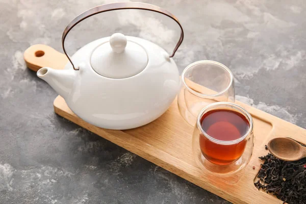 Koyu arka planda bir fincan siyah çay ve çaydanlık ile ahşap tahta, yakın plan.