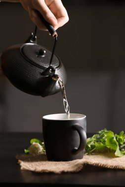 Kafedeki masada sıcak çayı bardağa dolduran kadın.