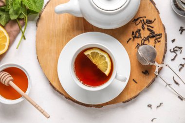 Beyaz zemin üzerinde siyah çay ve limon olan tahta, yakın plan.