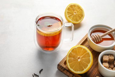 Beyaz arka planda limon, bal ve kamış şekerli bir bardak siyah çay, yakın plan.