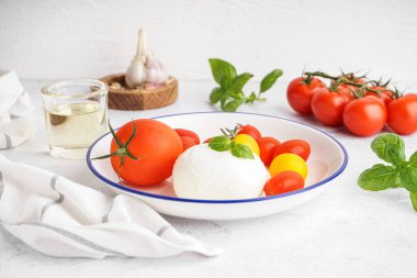Lezzetli mozzarella peynirli tabak ve açık arkaplanda taze domates.