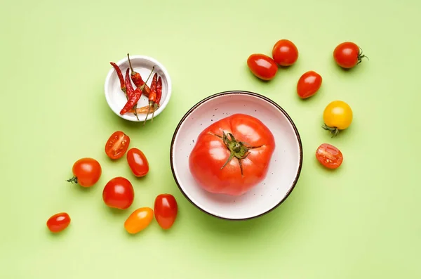 Composition with fresh tomatoes and dried chili peppers on green background