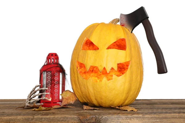 Jack-O-Lantern pumpkin with axe, lantern, skeleton hand and leaves on table against white background