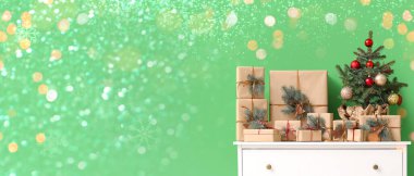 İçinde Noel ağacı olan çekmeceler ve odada yeşil duvarın yanında hediyeler.