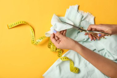 Kadın terzi renk arkaplanında makasla kumaş kesiyor