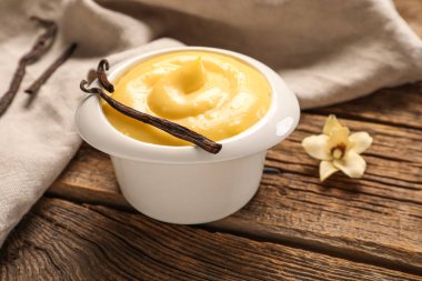 Ahşap arka planda lezzetli vanilyalı puding ramekin, yakın plan