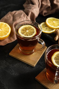 Koyu arkaplanda cam çay ve limonla dikil. Yakın plan.