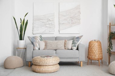 Gri kanepe, puf ve 3 boyutlu tekstil sanat eserleriyle modern oturma odasının içinde.