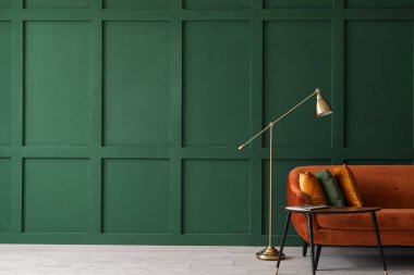 Şarjörlü masa, kırmızı kanepe ve yeşil duvarın yanındaki lamba.