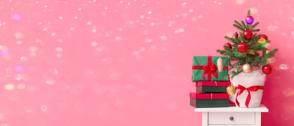 クリスマスツリーとテキストのためのスペースを持つピンクの背景とテーブルの上の異なるプレゼント — ストック写真