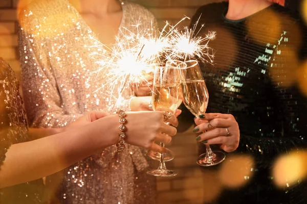 Evde şampanya bardakları ve Noel ışıkları olan kadınlar, yakın plan.