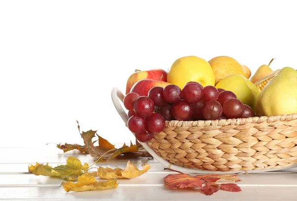 Rieten Schaal Met Vers Fruit Herfstbladeren Tafel Tegen Witte Achtergrond — Stockfoto