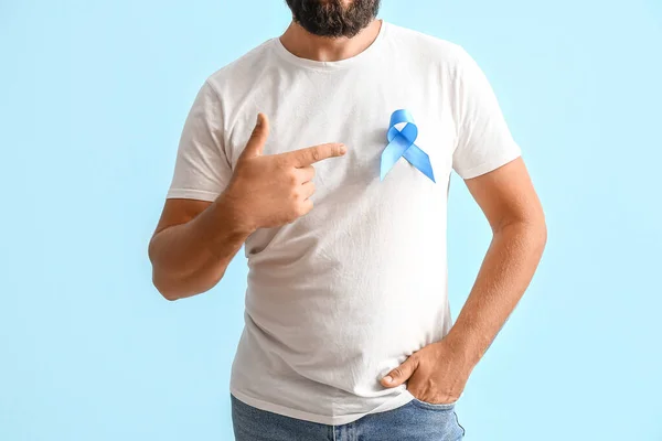 Man with blue awareness ribbon on color background. Prostate cancer concept