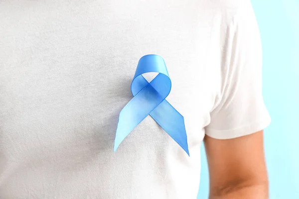Man with blue awareness ribbon on color background. Prostate cancer concept