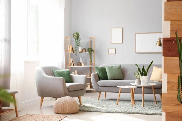 Interior of modern living room with houseplants, sofa and armchair