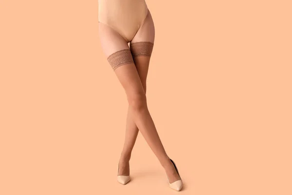 Woman in nude stockings and heels on beige background