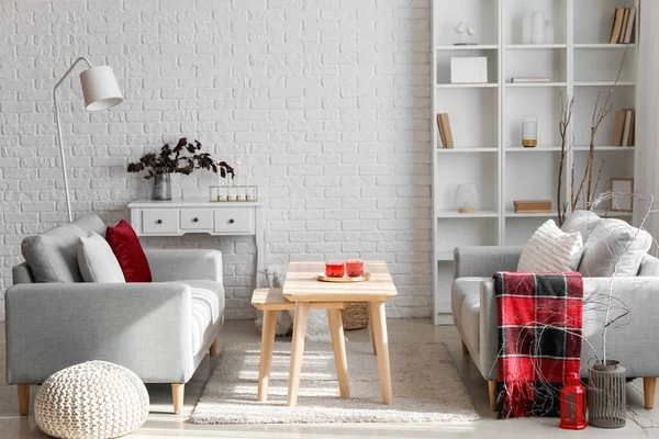 Gri kanepeleri, masa ve ağaç dalları olan modern oturma odasının içinde.