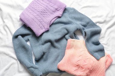 Beyaz kumaş arka planda farklı çocuk süveterleri.