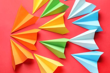 Colorful paper planes on red background