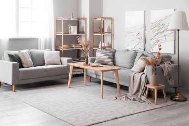 Kanepeleri, masası ve 3 boyutlu tekstil tablosu olan modern oturma odası.