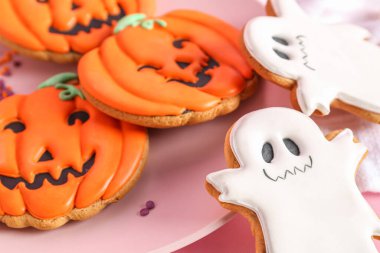 Pembe arka planda Cadılar Bayramı kurabiyeleri olan tabak, yakın plan.