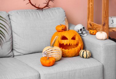 Oturma odasındaki koltukta insan kafatası olan Cadılar Bayramı balkabakları.