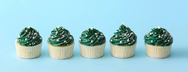 Tasty Christmas cupcakes on blue background