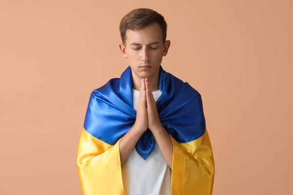 Junger Mann Mit Ukraine Fahne Betet Auf Beigem Hintergrund — Stockfoto