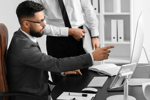 Handsome bank manager working with his assistant at table in office