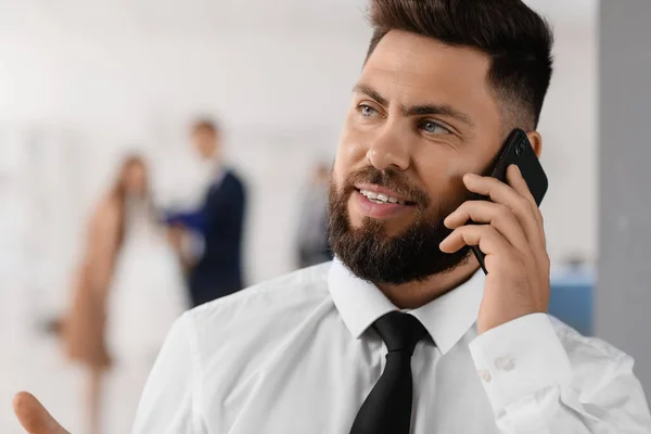 Handsome bank manager talking by mobile phone in office, closeup