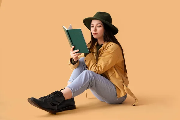 若いです女性でジャケット読書本上のベージュの背景 — ストック写真