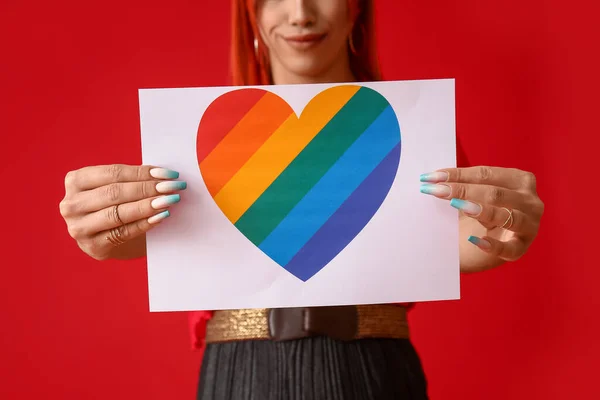 Stylish Transgender Woman Holding Paper Sheet Rainbow Heart Red Background — Stock Photo, Image