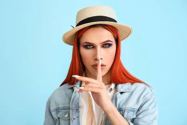 Stylish transgender woman showing silence gesture on blue background