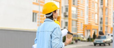 Ev planı ve bir fincan kahvesi olan kadın inşaat işçisi.