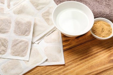 Ahşap arka planda bir kase su ve havluyla hardal alçıları, yakın plan.