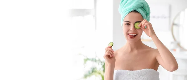 Beautiful young woman with cucumber slices after shower in bathroom. Banner for design
