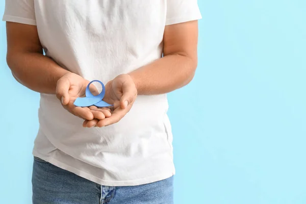 Man with blue awareness ribbon on color background. Prostate cancer concept