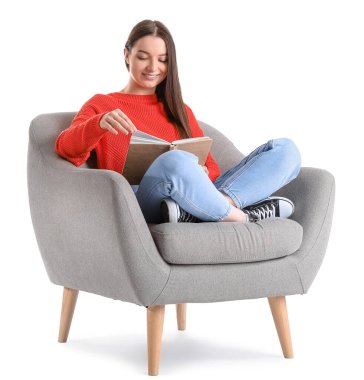 Beyaz arka planda yumuşak koltukta kitap okuyan genç bir kadın.