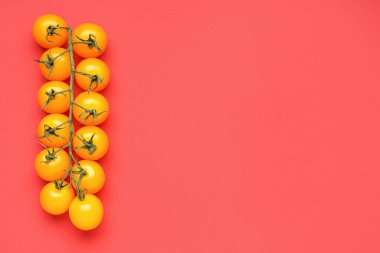 Kırmızı zemin üzerinde olgun sarı domatesler.