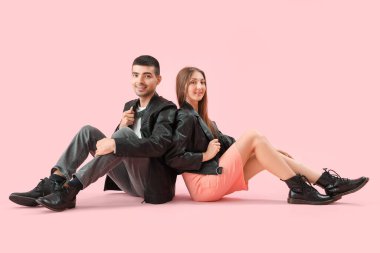 Pembe arka planda, sonbahar elbiseli şık genç bir çift.