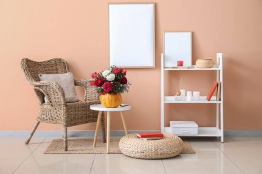 Balkabağı ve koltukta sonbahar çiçekleri olan şık bir oturma odası.