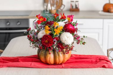 Mutfaktaki yemek masasında sonbahar çiçekleri olan balkabağı.