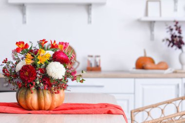 Mutfaktaki yemek masasında sonbahar çiçekleri olan balkabağı.